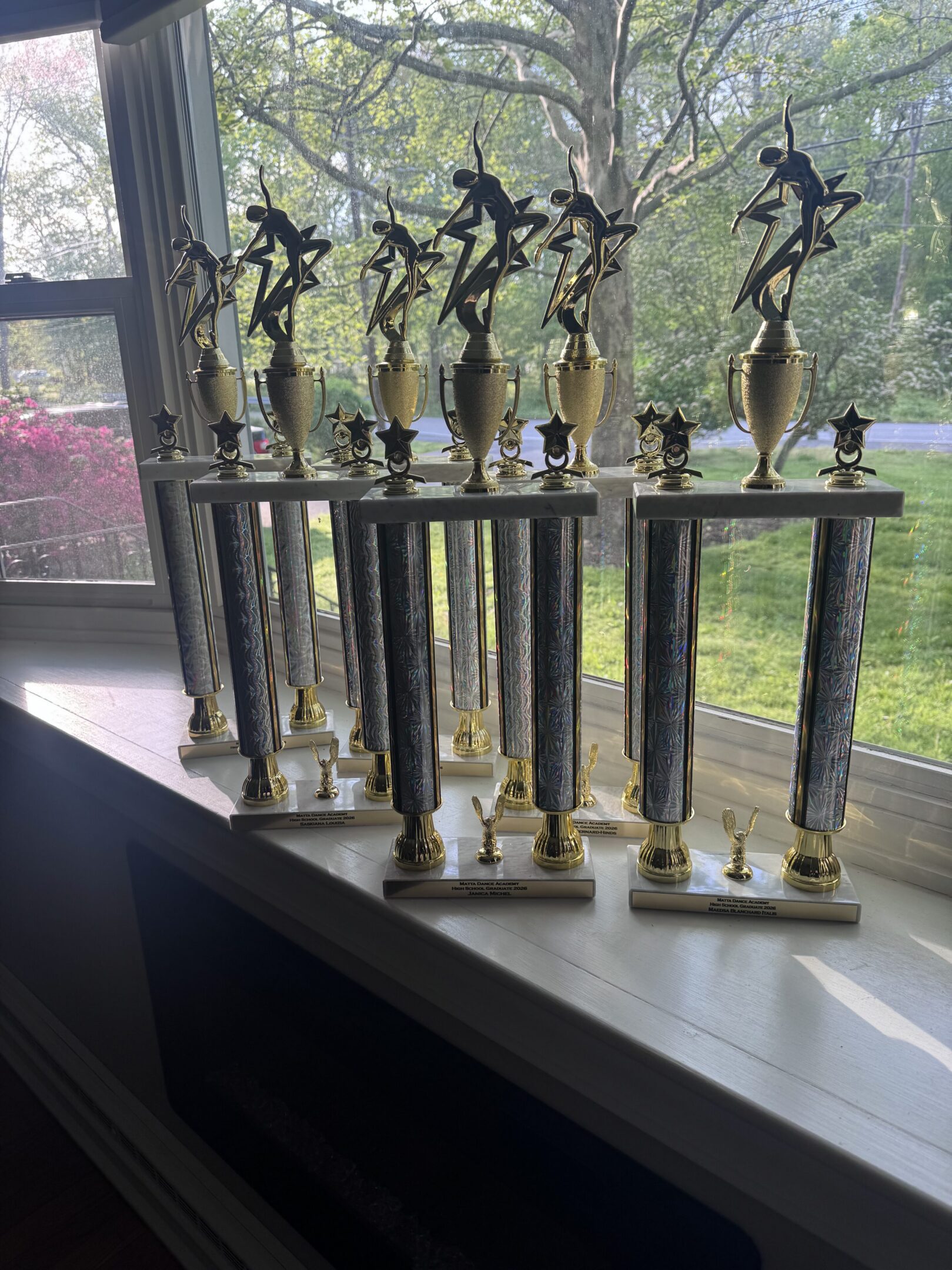 Row of tall dance trophies on windowsill