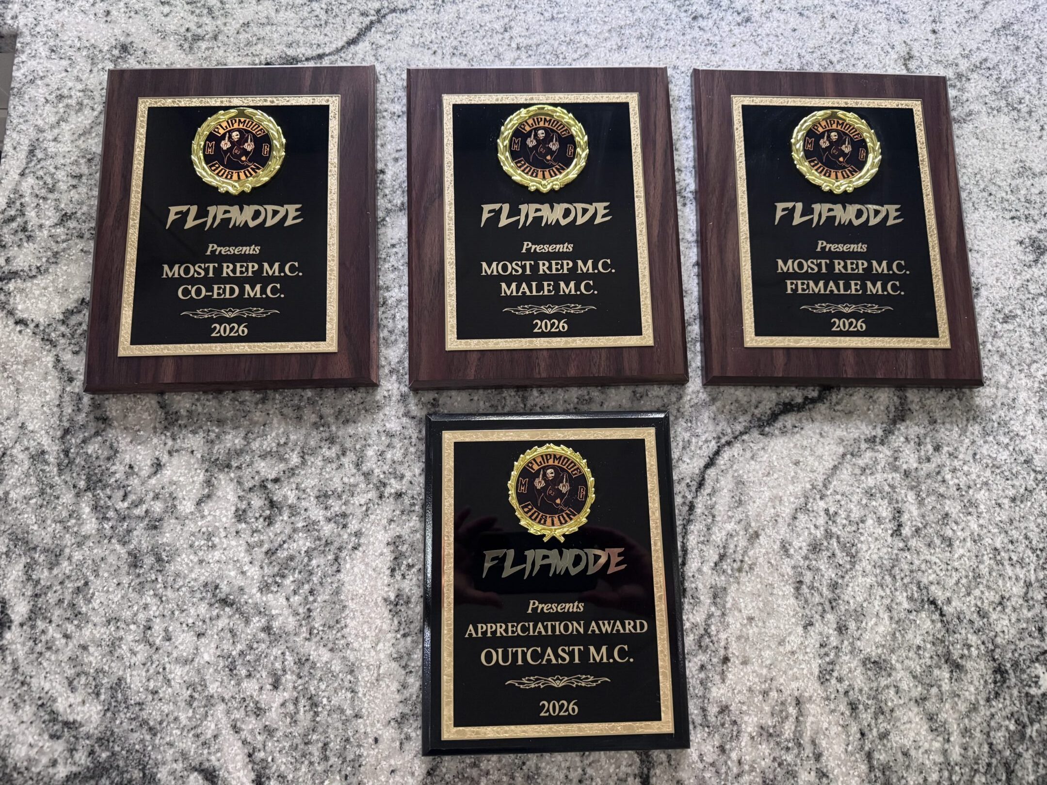 Four wooden award plaques on granite countertop