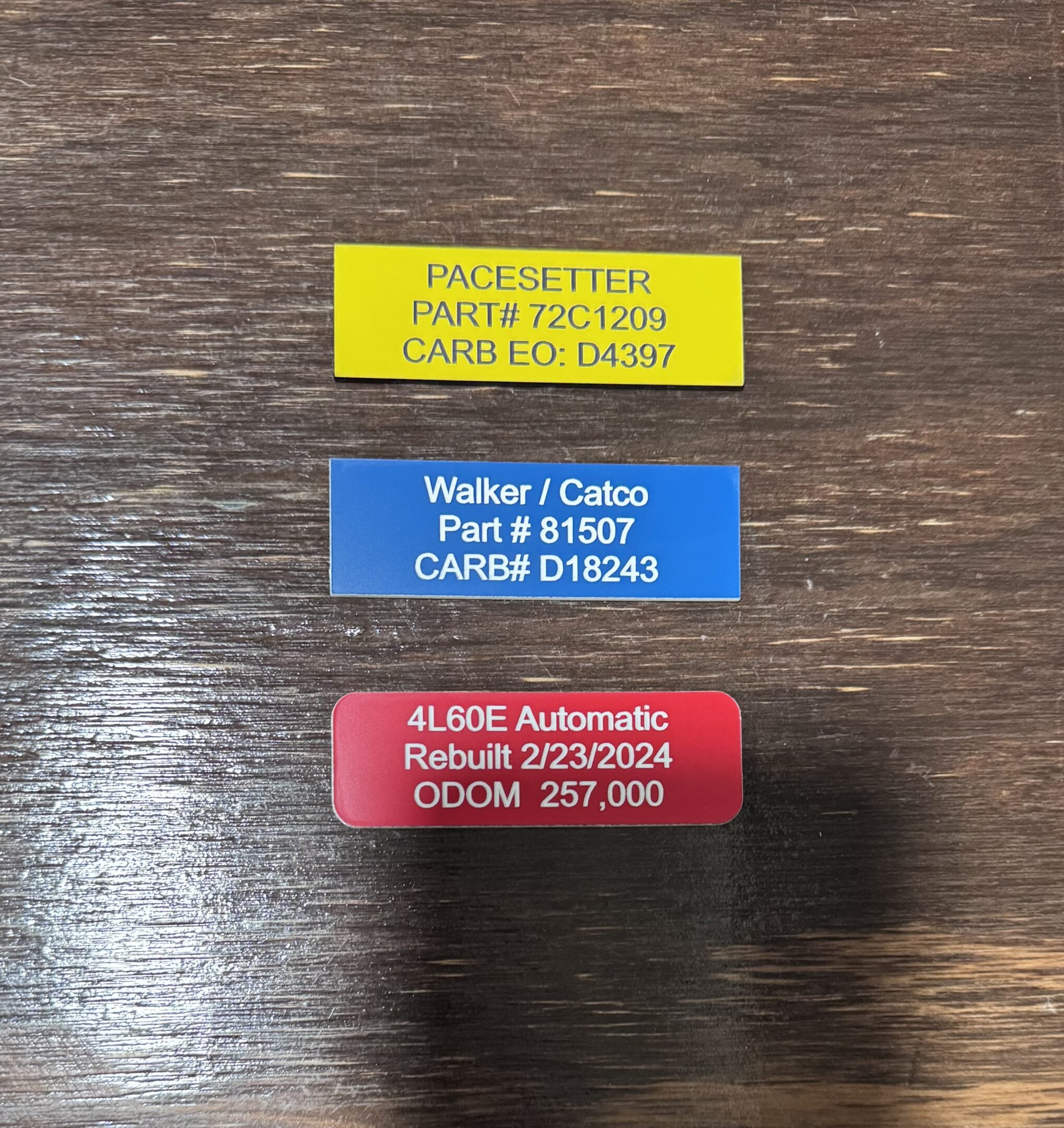 Three colored automotive part labels on wood